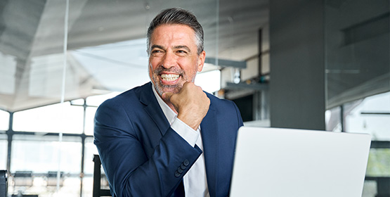 a smiling man working on a laptop